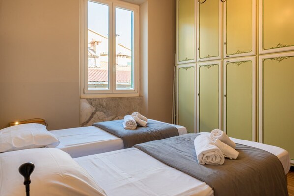 A hotel room with two beds, a window, and a green wardrobe.