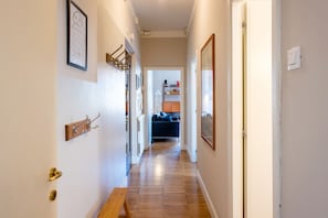 Un pasillo con un banco, un perchero y una puerta que da a una habitación con un sofá azul.