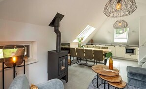 Un appartement moderne de style «loft», doté d’un poêle à bois, d’un coin repas et d’une cuisine avec une lucarne.