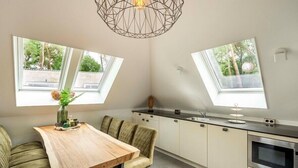 Eine moderne Küche mit Esstisch, Stühlen, einem Backofen und Oberlichtern.