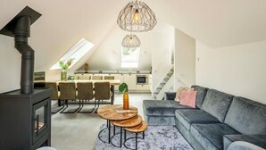 Eine moderne Lofts-Wohnung mit Essbereich, einer Couch, einem Kamin und einer Küche mit Treppe.