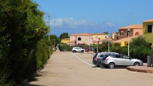 Ein Parkplatz mit Autos, einem Bürgersteig und Gebäuden im mediterranen Stil.