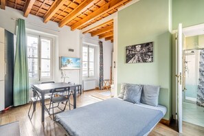 A room with a bed, a table, and a chair, a window with curtains, and a painting on the wall. - GuestHost - NEW! Elegant apartment 1.5km from P.ta Venezia (Milano)