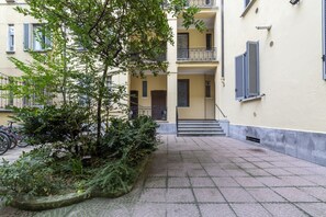 A courtyard with a staircase leading to an upper floor, surrounded by buildings with balconies and shutters. - GuestHost - NEW! Elegant apartment 1.5km from P.ta Venezia (Milano)