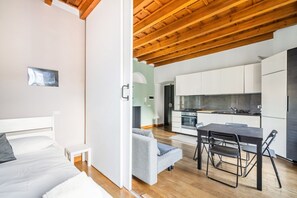 A modern apartment with a kitchen, dining area, and a bedroom with a bed and a nightstand. - GuestHost - NEW! Elegant apartment 1.5km from P.ta Venezia (Milano)