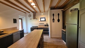 Eine moderne Küche mit Holzbalken, einer zentralen Kochinsel und einem Einbaukühlschrank.