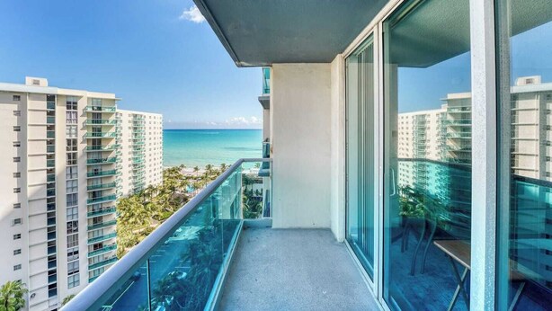 A balcony with a view of the ocean and adjacent high-rise buildings. - Great apartment in Hollywood with side ocean view! Direct exit to the beach! (Hollywood)
