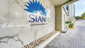 A marble wall with the logo and name 'SIAN OCEAN RESIDENCES' and a paved walkway with a small garden area. - Great apartment in Hollywood with side ocean view! Direct exit to the beach! (Hollywood)