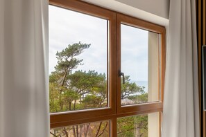 Une fenêtre donnant sur des arbres et un plan d’eau.