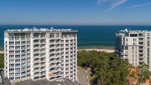 Ein Hochhaus mit mehreren Balkonen, Blick auf das Meer und ein Strand im Hintergrund.