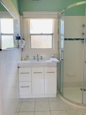 A modern bathroom with a glass shower enclosure, a sink with a mirror, and a window above the sink. - Beautiful scenery in Glenorchy with mountain and water view (Glenorchy)