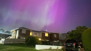 A residential area with houses and a parked SUV under a night sky with visible stars and aurora. - Beautiful scenery in Glenorchy with mountain and water view (Glenorchy)