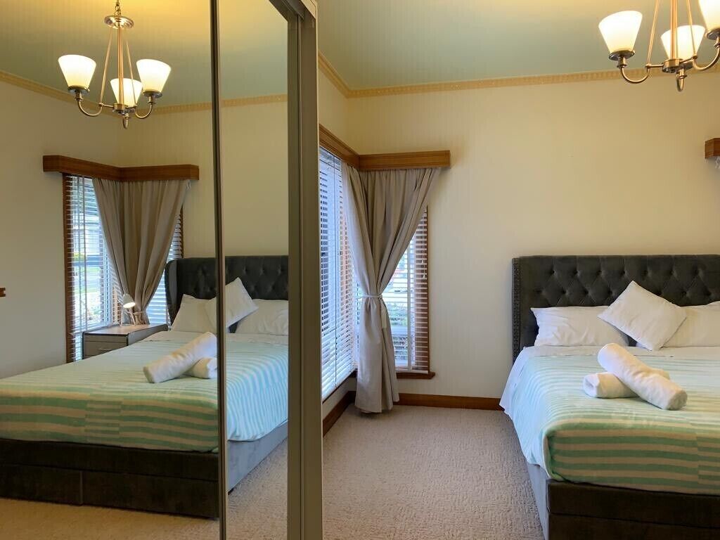 Quarto de hotel com duas camas, um espelho grande e um candelabro.