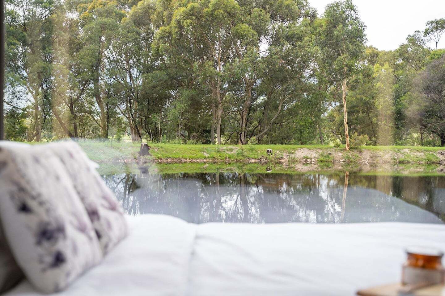 Un dormitorio con vistas a un lago rodeado de árboles.