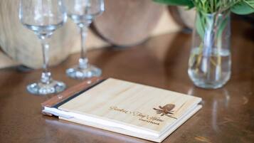 Ein Gästebuch aus Holz mit der Aufschrift "Parkside Jump Home guest book" auf einem Tisch mit Weingläsern und einem Blumenstrauß.