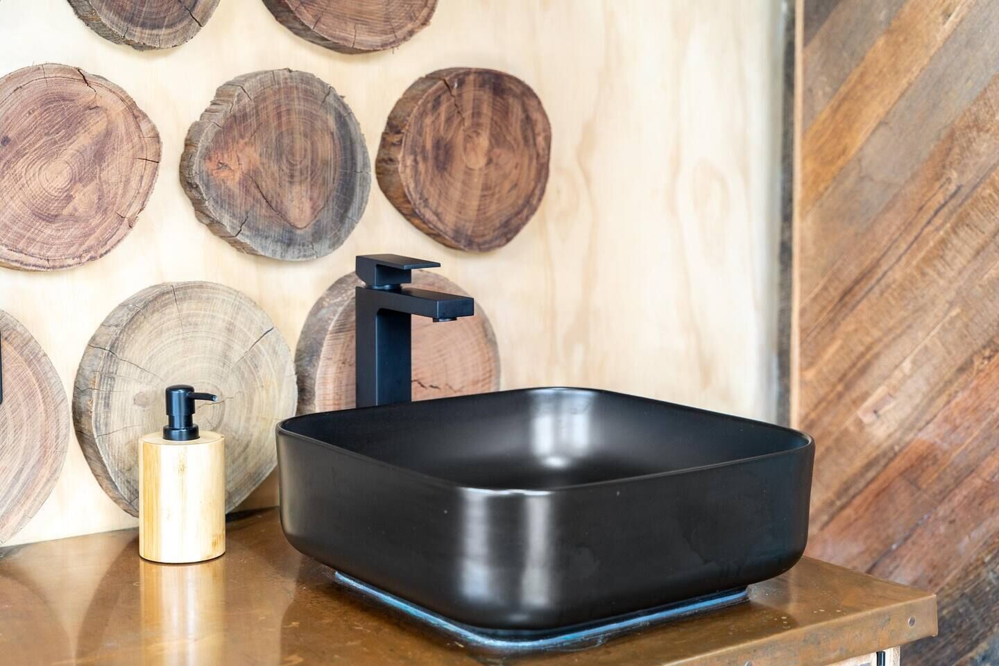A black rectangular sink with a modern faucet on a wooden countertop.