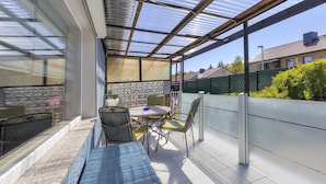 A covered patio with a table and chairs, a bench, and a view of the neighborhood. - Haus Nr. 9 (Wolgast)