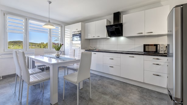 A modern kitchen with white cabinetry, a black range hood, and a built-in microwave. - Haus Nr. 9 (Wolgast)