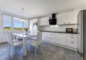 A modern kitchen with white cabinetry, a black range hood, and a built-in microwave. - Haus Nr. 9 (Wolgast)