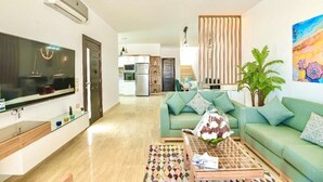 Un salon moderne avec un téléviseur à écran plat, un canapé vert, une table basse et une plante décorative.