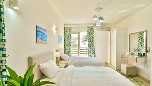 Une chambre d’hôtel avec deux lits, un bureau, un miroir et une vue sur l’extérieur.