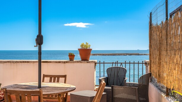 A terrace with a table and chairs, a potted plant, and a view of the sea. - Siracusa Horizon Home by Wonderful Italy (Siracusa)