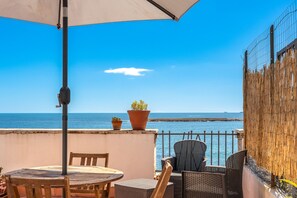 A terrace with a table and chairs, a potted plant, and a view of the sea. - Siracusa Horizon Home by Wonderful Italy (Siracusa)