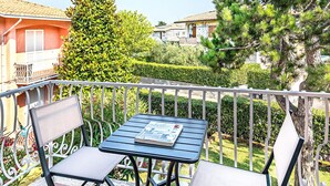 Un balcón con una mesa y dos sillas, con vista a una zona residencial con casas y árboles.