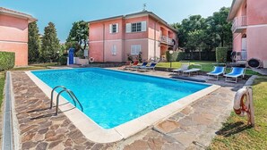 Una piscina con sillones de descanso, un flotador salvavidas y un deck de piedra.