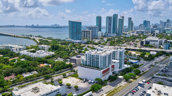 A high-rise hotel with multiple floors, surrounded by greenery and a busy urban area with roads and other buildings.