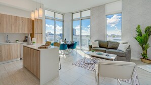 A modern apartment with a kitchen, dining area, and living room. It features large windows, a city view, and a cozy seating area. - DESIGN DISTRICT LUXURY 2/2 PARADISE Q602 (Miami)