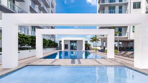 A modern pool area with a clear blue pool, white pillars, and a view of the surrounding buildings. - DESIGN DISTRICT LUXURY 2/2 PARADISE Q602 (Miami)