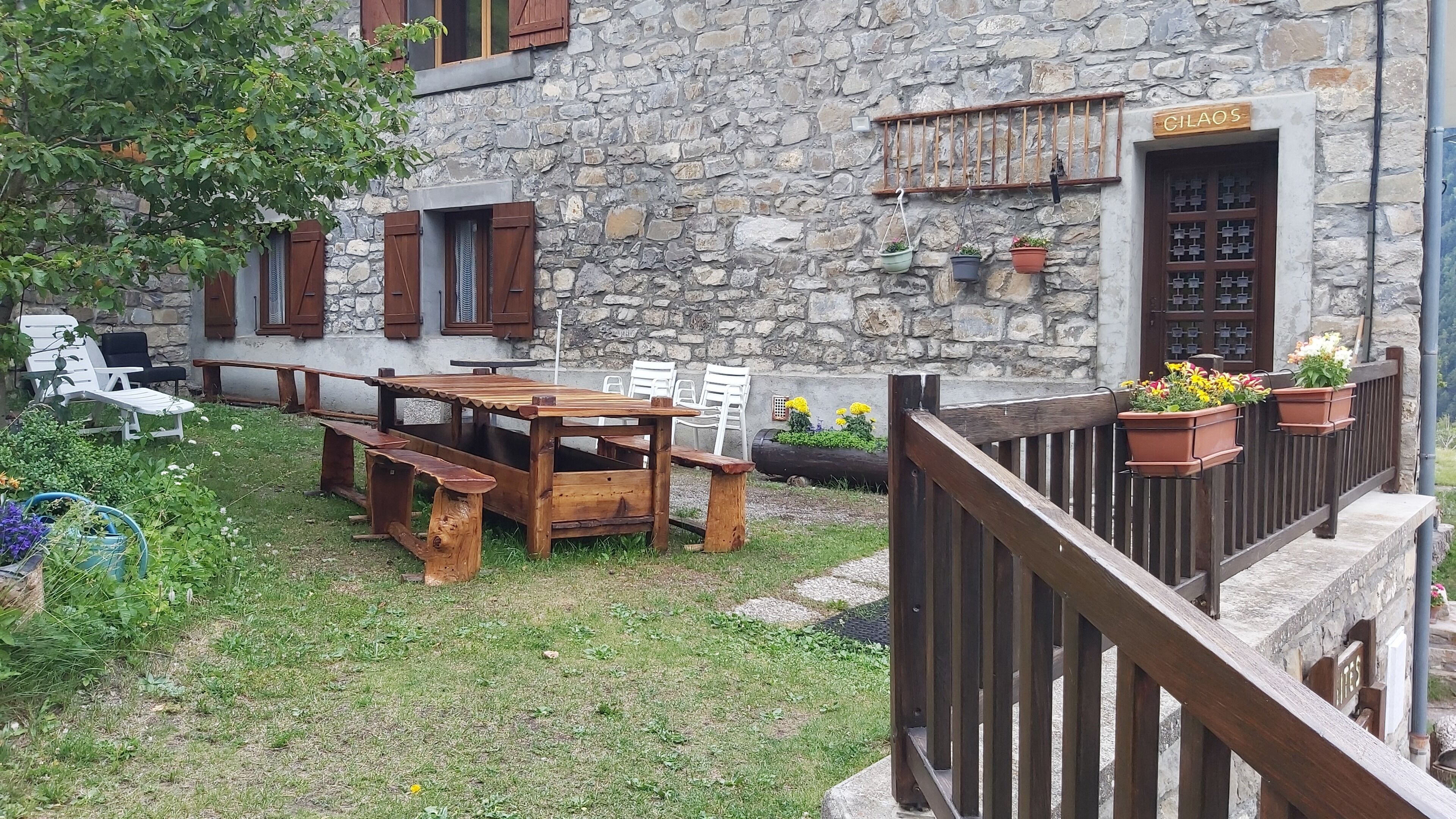 A stone building with a wooden table and chairs in the yard.