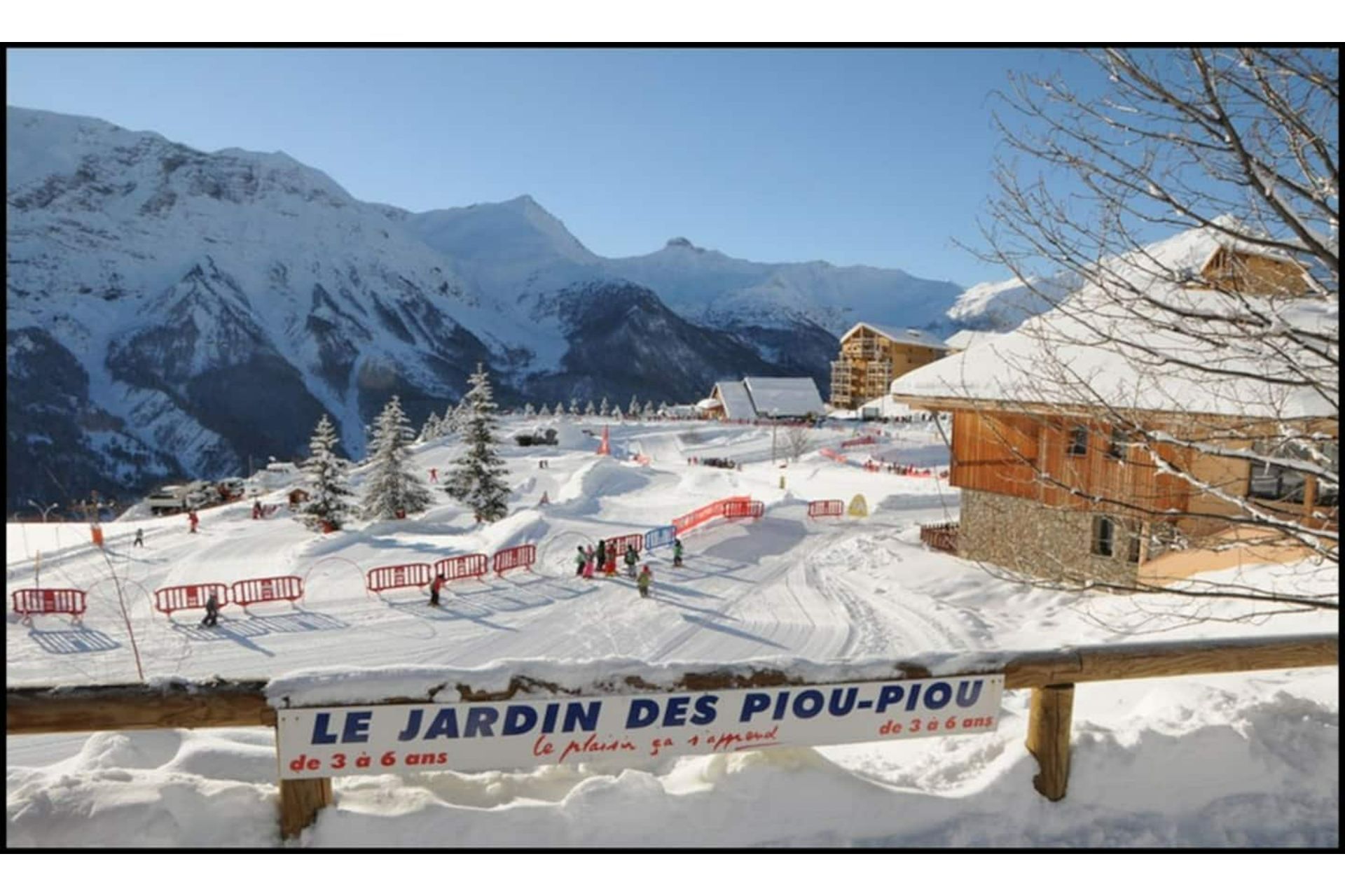 A snowy mountain landscape with a sign reading "LE JARDIN DES PIOU-PIOU de 3 à 6 ans".