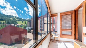 Ein modernes Zimmer mit großen Fenstern, einer Holztür und Blick auf eine gebirgige Landschaft.
