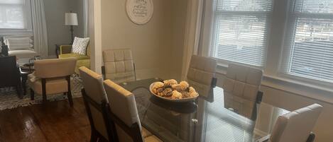 A dining area with a glass table, cushioned chairs, and a bowl of food.