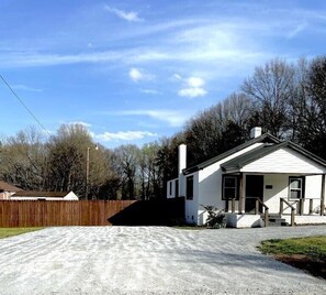 A single-story house with a front porch, a chimney, and a driveway leading to the entrance. - Private, pet-friendly adorable getaway mins to downtown (Greenville)