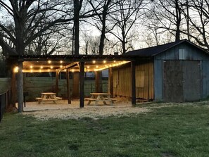 A covered outdoor area with string lights, two picnic tables, and a shed. - Private, pet-friendly adorable getaway mins to downtown (Greenville)