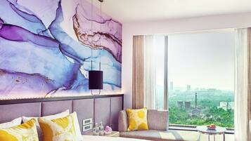 Een moderne hotelkamer met een groot bed, een bank, uitzicht over de stad en een marmeren wand.