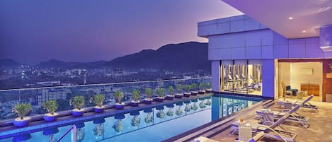 A rooftop pool with lounge chairs and a view of the cityscape.