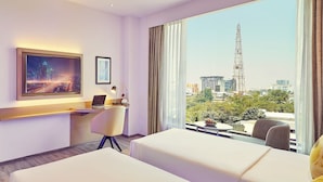 Habitación de hotel con vistas a la ciudad, un escritorio con una computadora portátil, una cama y una silla.