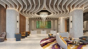 Un lobby moderno con un área de descanso curva, un cuadro abstracto de gran tamaño y un diseño de techo singular.