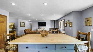 Un salón espacioso con una gran mesa de comedor de madera, asientos cómodos y una chimenea.
