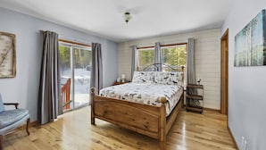 Une chambre à coucher avec un lit en bois, une table de chevet, une chaise et un tableau accroché au mur.