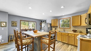 Une cuisine moderne avec des meubles en bois, un îlot central et un coin repas doté de chaises en bois.