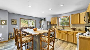 Una cocina moderna con armarios de madera, una isla central y un comedor con sillas de madera.