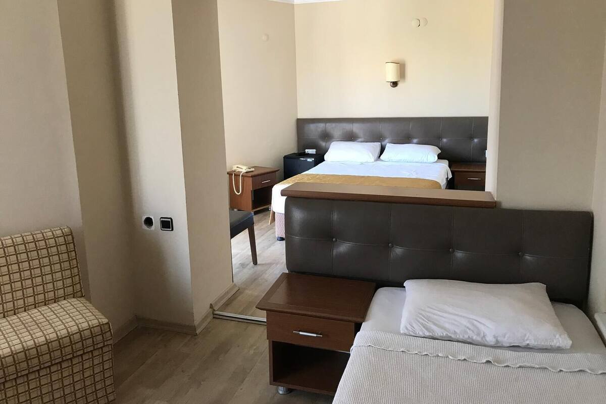 A hotel room with a bed, bedside table, and a chair.