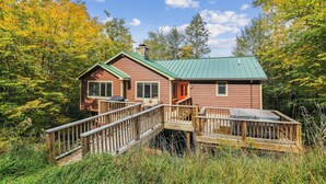 Een chalet met een groen dak, houten terras en een klein terras.