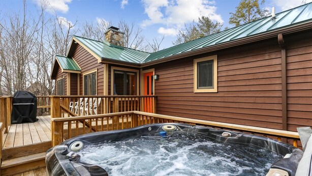 Een hottub op een houten terras, met een huis op de achtergrond.