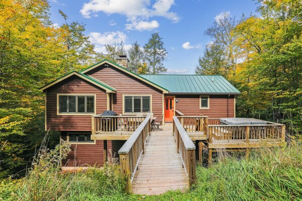 A rustic cabin with a green roof, a wooden deck, and a covered outdoor seating area. - Slopeside on Timberline Mountain's Salamander Trail-Perfect in every season! (Canaan Valley)
